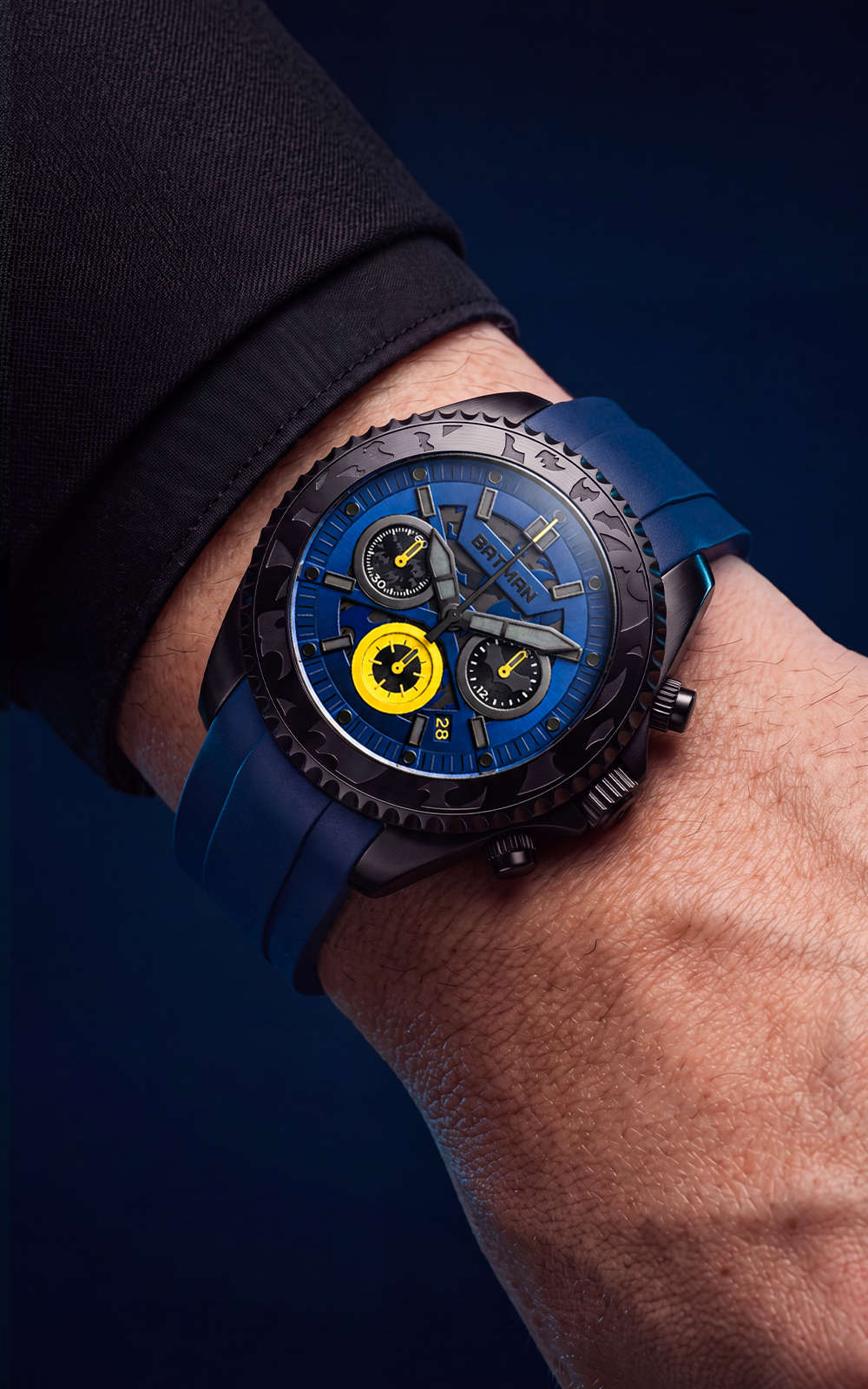 A close-up of a wrist wearing a rugged chronograph watch with a blue strap, black bezel, and a blue dial featuring yellow accents.