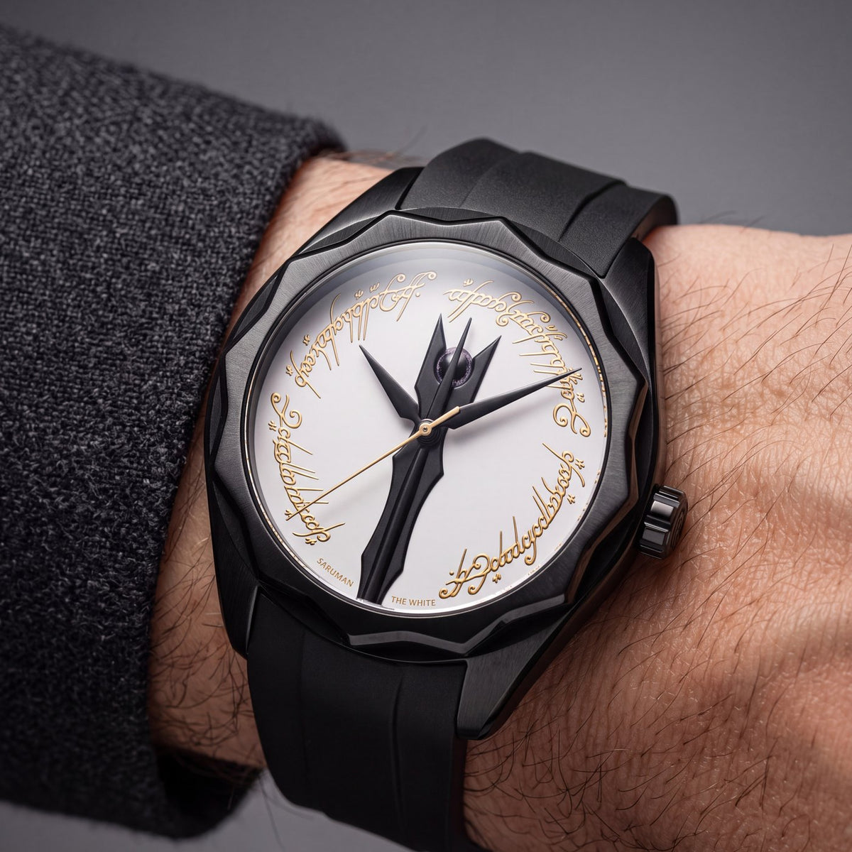 The Saruman watch worn on the wrist on its black rubber strap, the white dial and gold Elvish script above a charcoal knit cuff